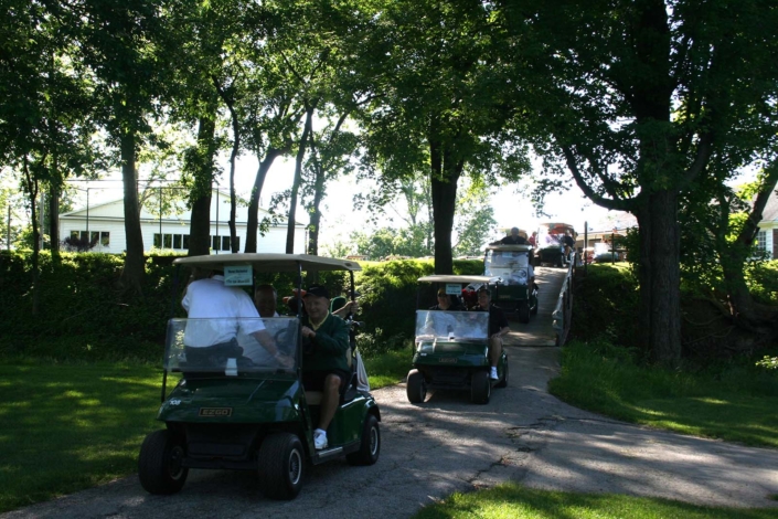 line of golf carts riding down the cart path