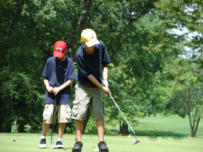two junior golfers putting